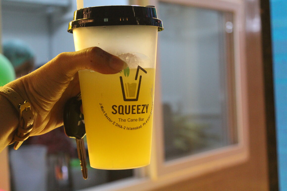 HASEEB ABBASI HOLDING A CUP OF JUICE BY SQUEEZY, HIS JUICE BAR.